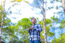 a man in a forest holding binoculars 