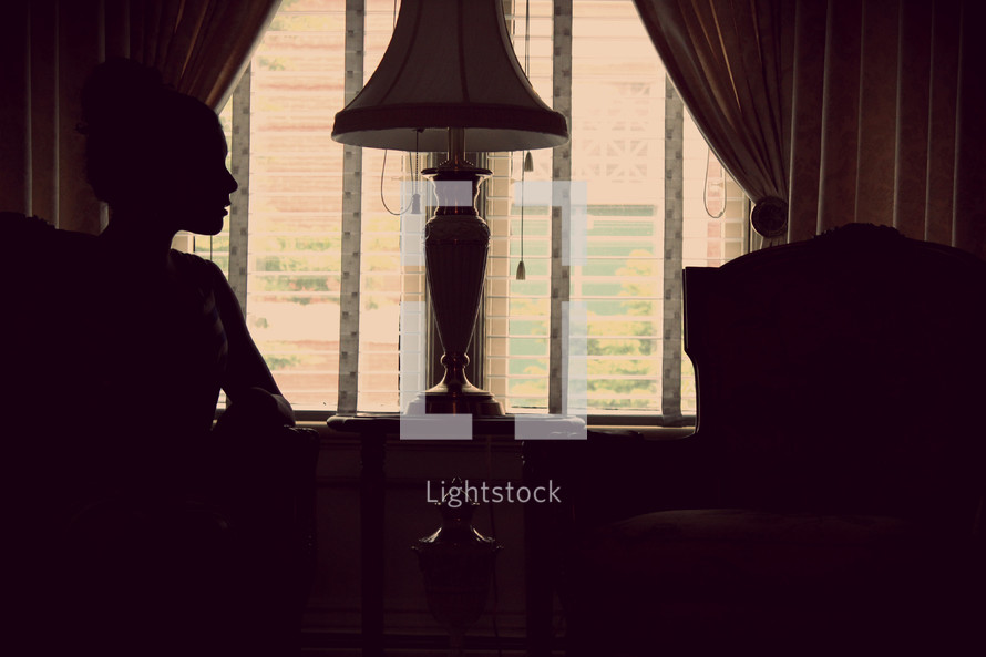 silhouette of a woman sitting in front of a window