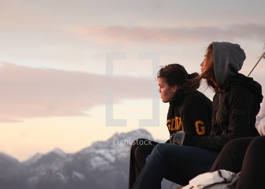women sitting on a mountain top enjoying the view 