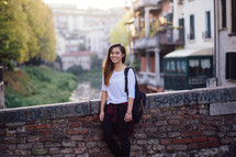 a teen girl standing outdoors next to a brick wall 