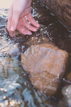 hand touching water in a stream 