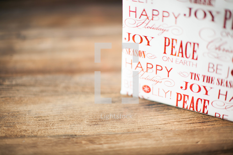 A Christmas present on a wood table - Peace and joy - wrapping paper