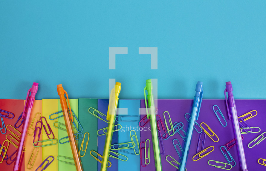 paperclips, mechanical pencils and paper in rainbow colors 