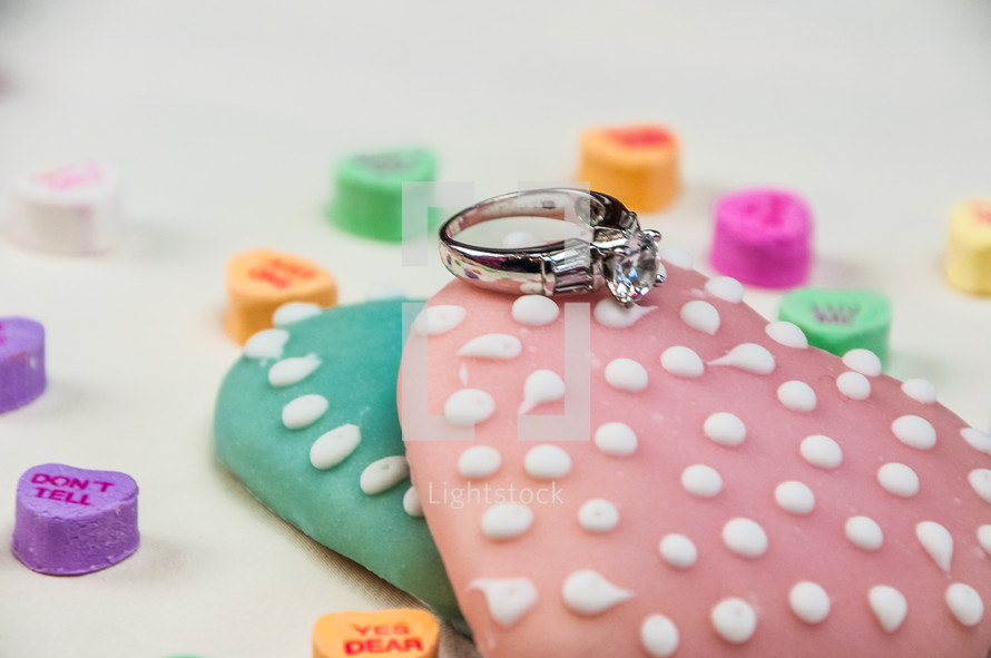 A diamond engagement ring on Valentine cookies and candies.