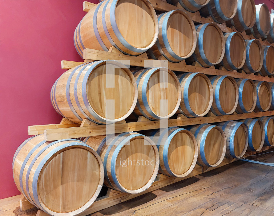 Wine barrels stacked in a pyramid shape are aging wine in a cellar