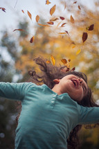 girl throwing fall leaves 