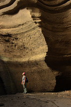man looking up standing in a cave 