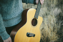 man in a sweater holding a Guitar