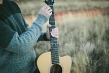 man holding a guitar outdoors 