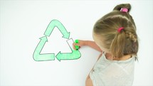 Caucasian girl colouring in an image of the recycle symbol