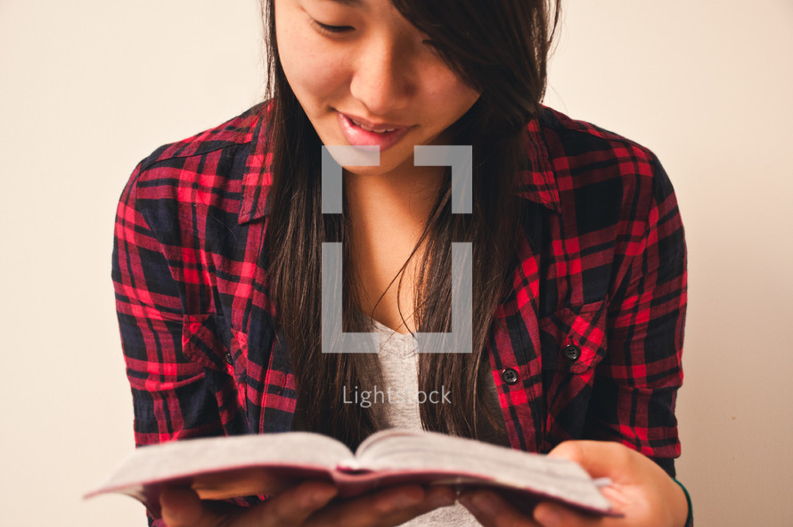 an Asian teen girl reading a bible 