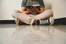 a man sitting on the floor reading a Bible 
