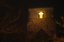 glowing cross in a church window at night 