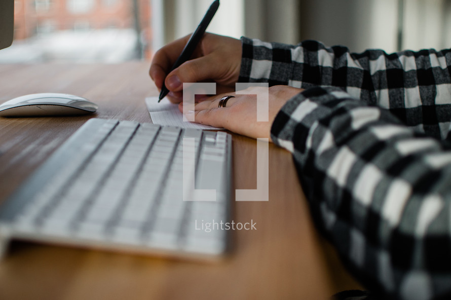 a man taking notes sitting at his computer 