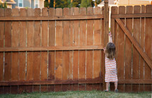 a child opening the latch of a gate