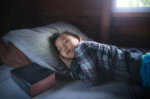 a child sleeping in bed next to a Bible 
