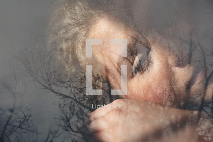 double exposure of a bare tree and woman's face - sorrow 