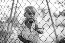 a child looking through a chain link fence 