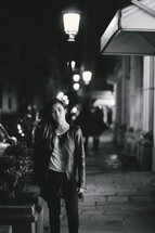 teen girl standing on a sidewalk at night 