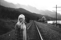 woman standing on railroad tracks 