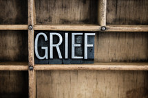 word grief in blocks on a bookshelf 