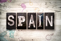 word Spain on white washed wood