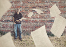 man reading a Bible as pages are being blown away