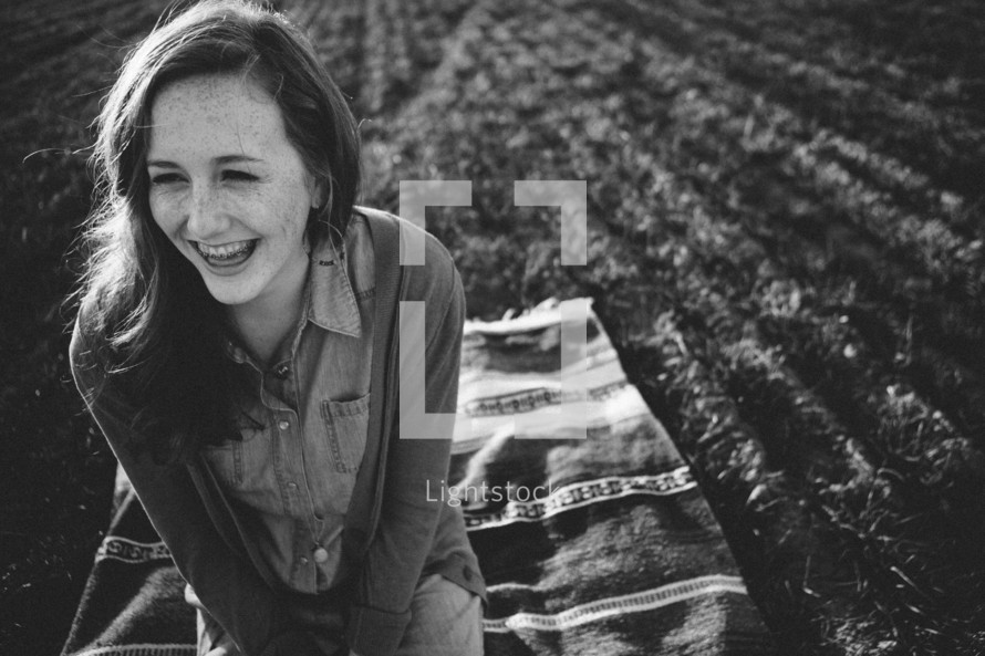 smiling teen girl sitting on a blanket in the grass