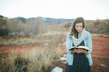 woman standing outdoors with an open Bible 