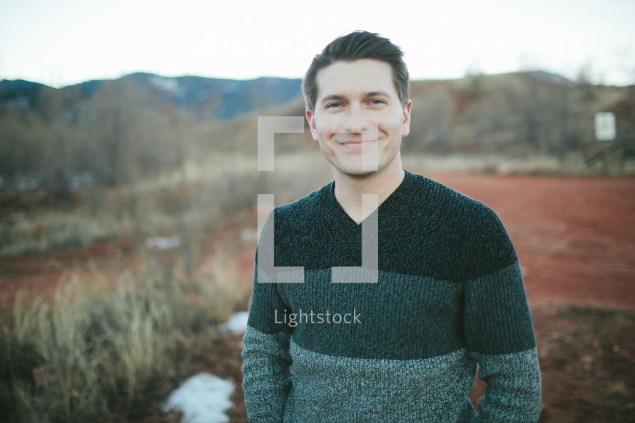 man in a sweater standing outdoors smiling 