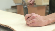man chiseling holes into wood 