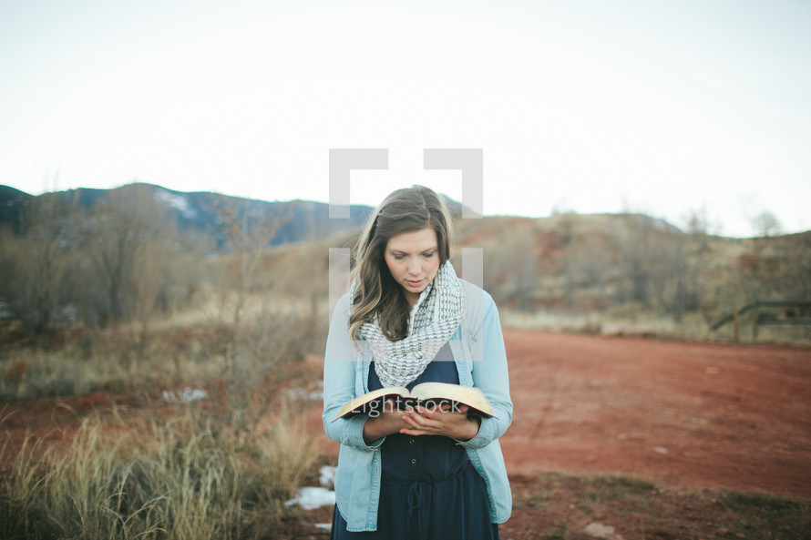 woman standing outdoors holding a Bible 