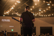a man playing a guitar at a worship service 