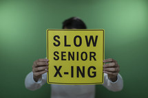 man holding up a Slow senior crossing sign 