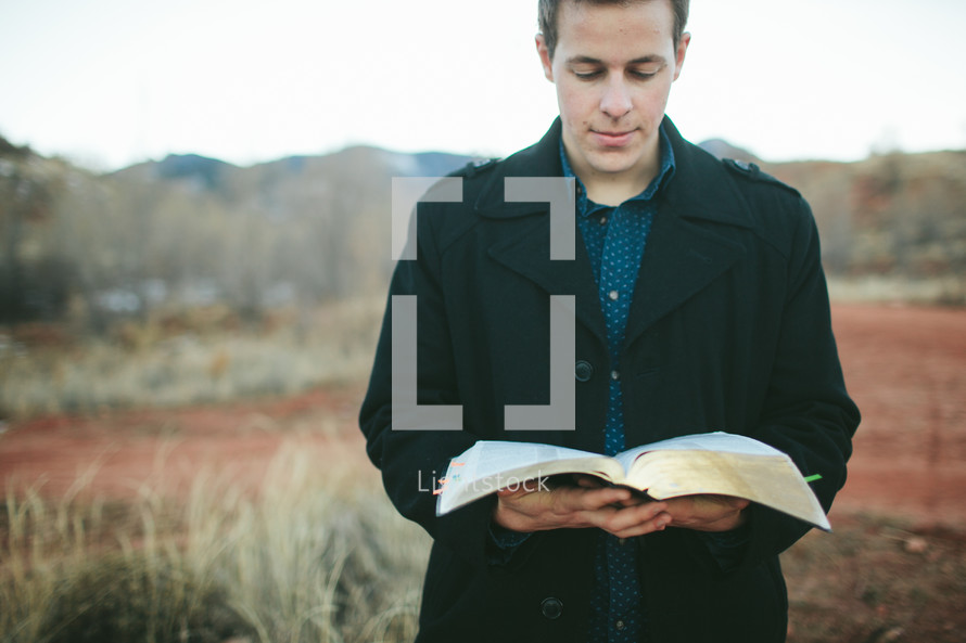 man reading a Bible outdoors 