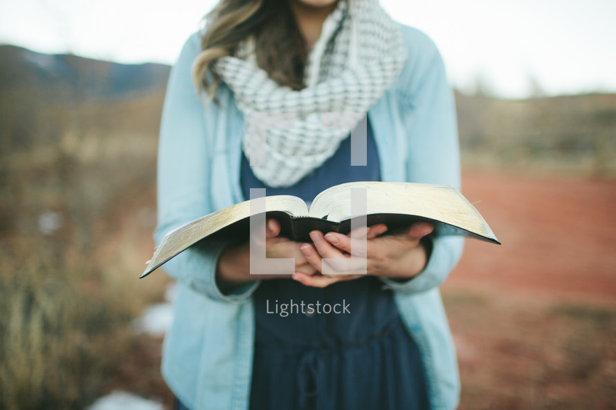 woman holding an open Bible outdoors 