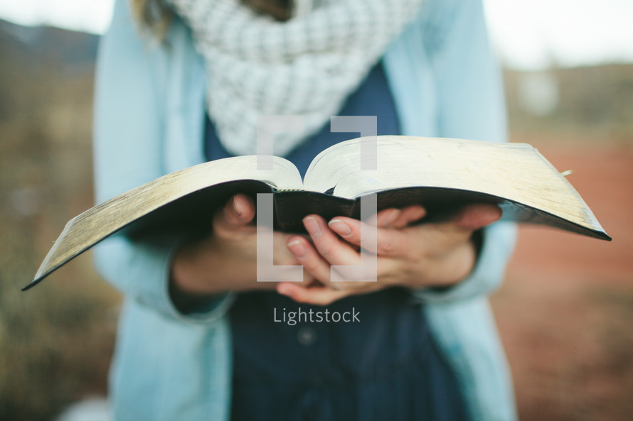 woman standing outdoors holding a Bible 