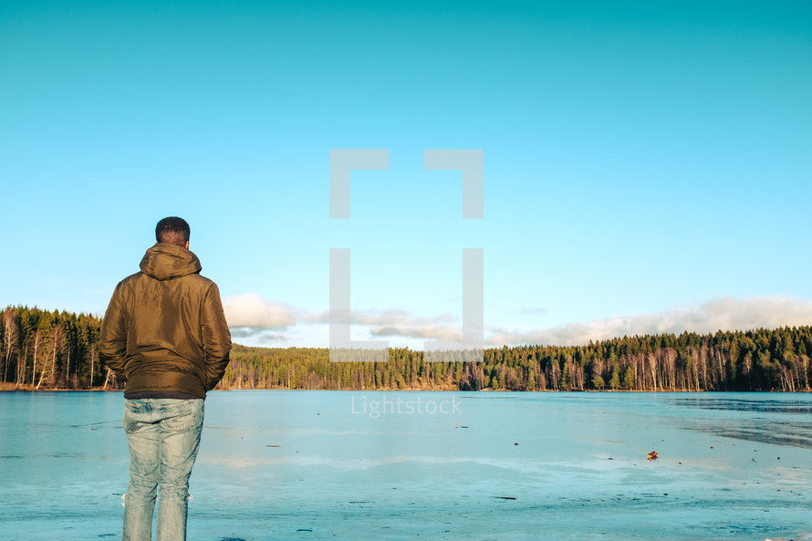 a man standing on a dock over a frozen lake 