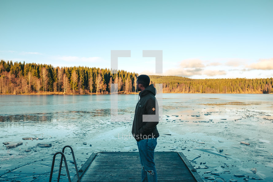 a man standing on a dock over a frozen lake 