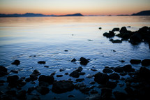 rocks along a shore at sunset 