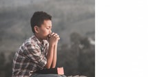 a boy praying outdoors 