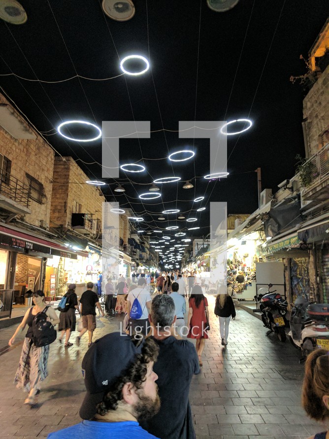 people walking through a market at night 
