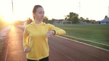 Concept healthy running. Young fitness woman running at the stadium. Runner woman with fitness tracker and running app wearable technology with smartwatch. Healthy lifestyle.