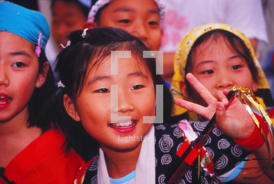 a young girl showing a peace sign 