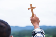 a man holding up a wooden cross