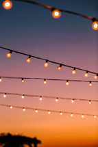 string of lights against an orange sky at sunset  