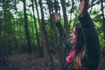 a woman with hands raised alone in a forest 