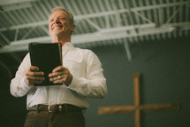Man holding Bible in front of cross.