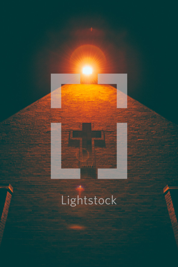 light over a cross on an exterior wall of a church 