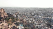 Jodhpur blue cityscape contrasting with Mehrangarh Fort in Rajasthan, India - Aerial Panoramic reveal shot
